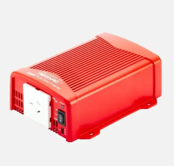 A red power inverter is sitting on top of the ground.